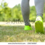 stock-photo-runner-woman-feet-running-on-grass-closeup-on-shoe-298799987